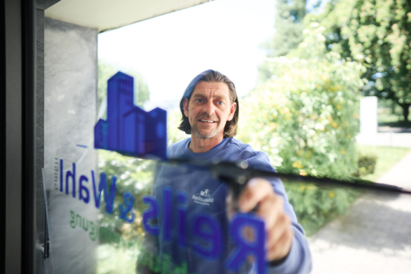 Mann reinigt große Glasfläche eines Unternehmens